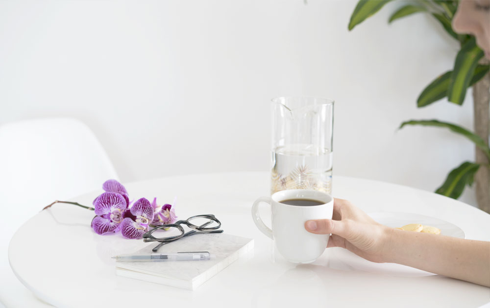 Eyeglasses on table with woman drinking coffee