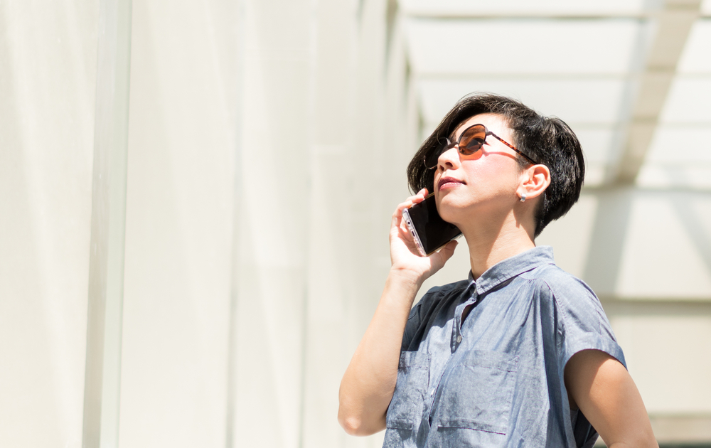 A woman wearing sunglasses and talking on the phone