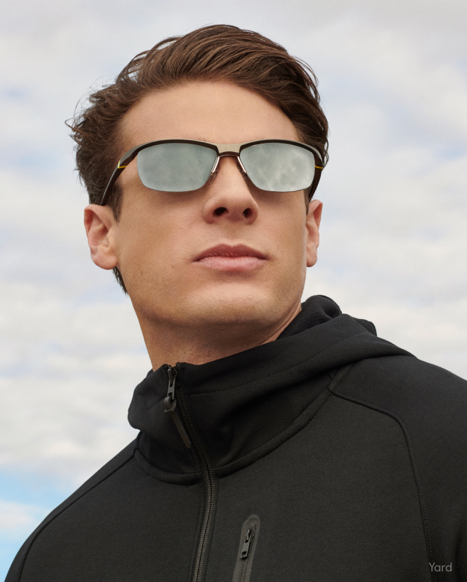 A man in a black jacket wearing mirrored sunglasses